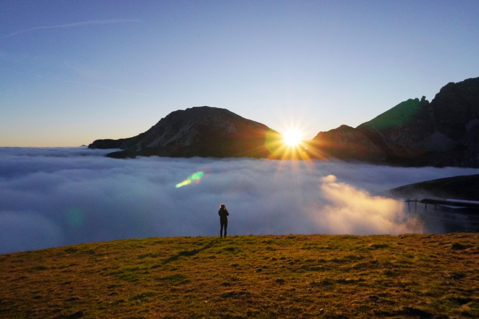A traveler looking over misty mountains at sunrise
